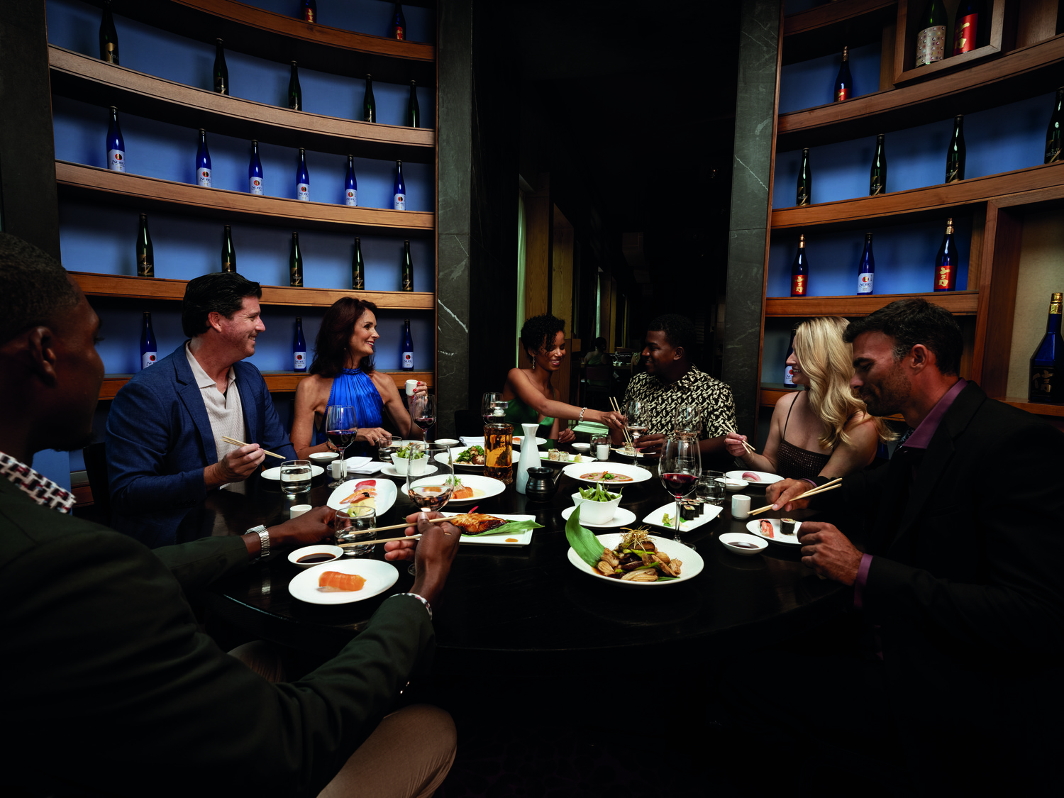 Friends dining together, sharing sushi and drinks at a stylish restaurant in the Bahamas.