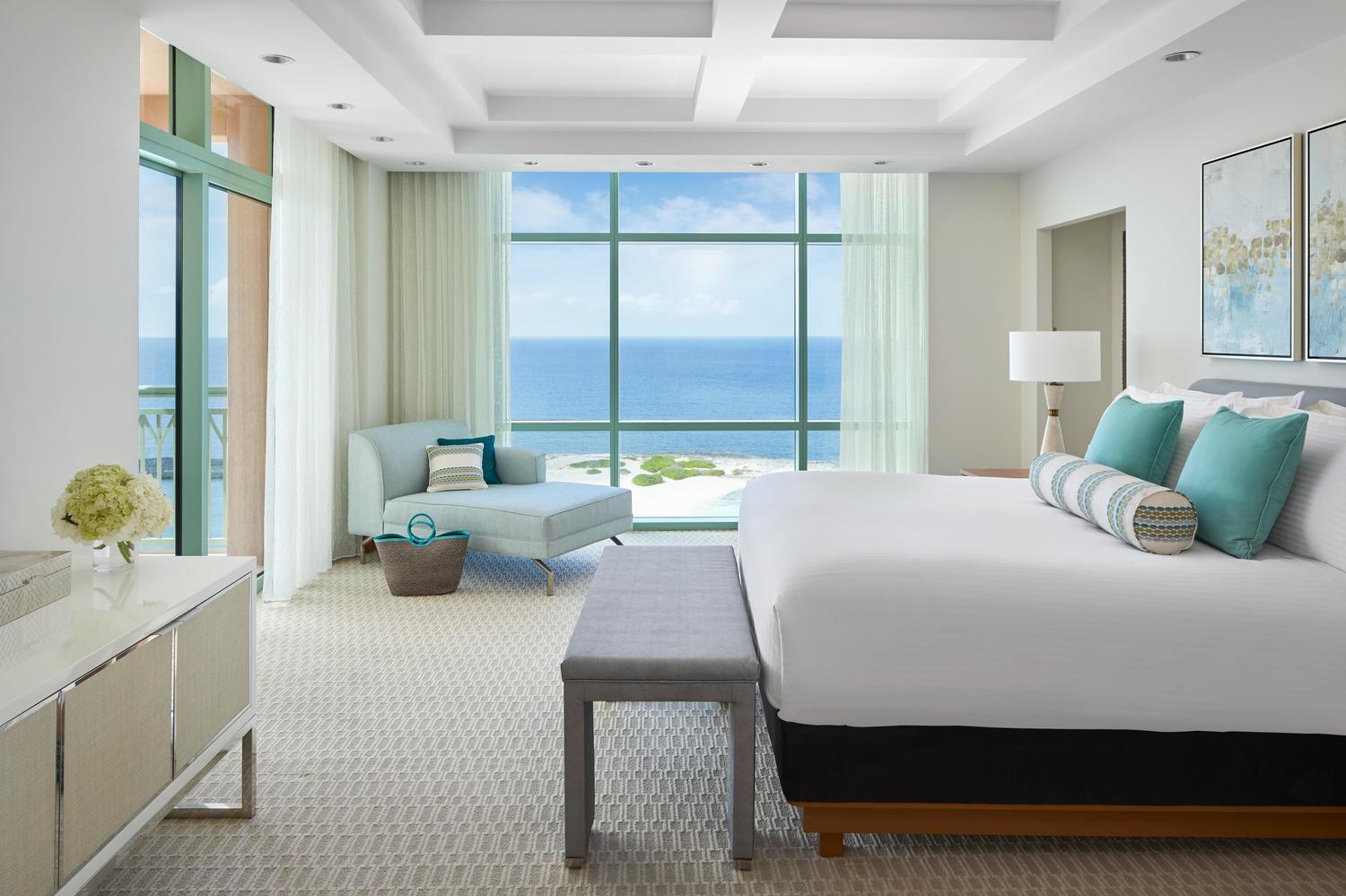 Luxurious suite at The Cove with a king bed, lounge area, and balcony overlooking the ocean.